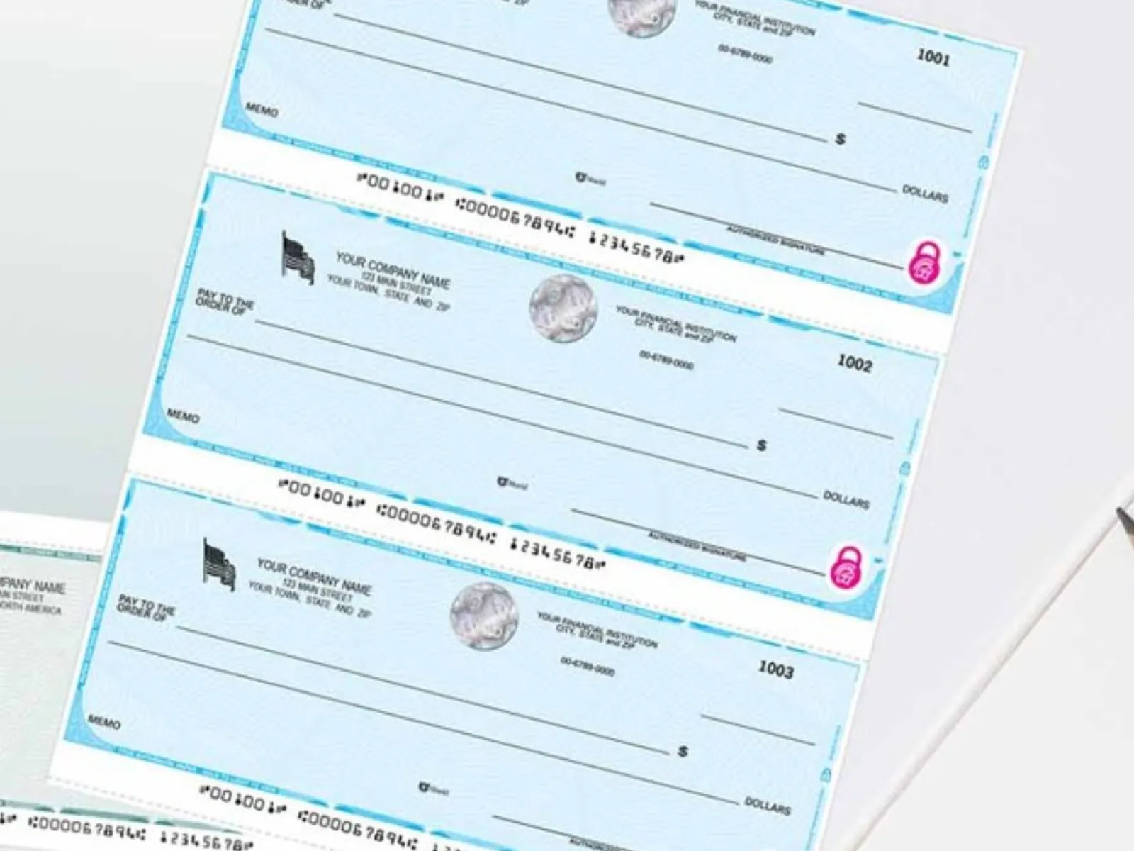 Three blank blue business checks with company info and security features laid out on a white desk.