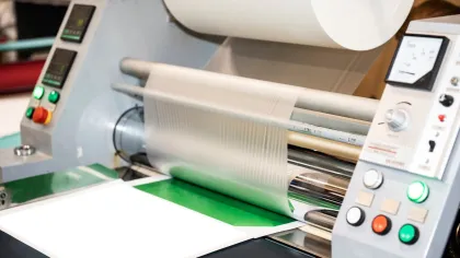 Close-up of a professional laminating machine in operation, showcasing controls and process details.