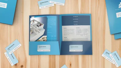 Real estate brochure and business cards for George Brown displayed on a wooden table in blue tones.